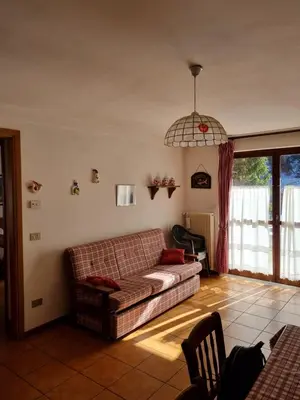 a living room with a couch and a window at Appartamento con giardino in Predazzo