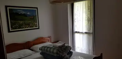 a bedroom with a bed and a window at Appartamento con giardino in Predazzo
