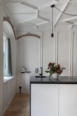 a kitchen with white walls and a ceiling with a black counter at Ida - historic town apartments in Vipiteno
