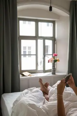 a woman laying in bed holding a cell phone at Ida - historic town apartments in Vipiteno