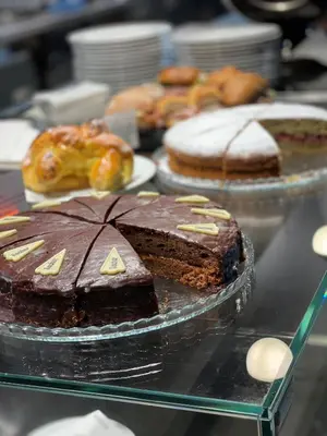 a glass table with different types of cakes and pastries at Hotel Restaurant Putzer in Naz-Sciaves