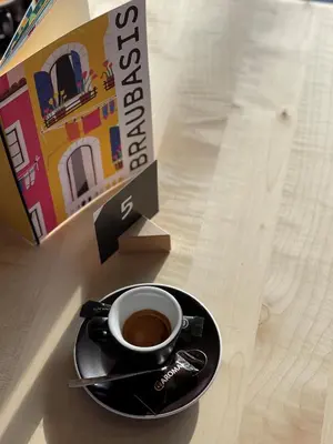 a cup of coffee on a plate next to a box at Hotel Restaurant Putzer in Naz-Sciaves