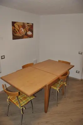 a wooden table with two chairs and a painting on the wall at Casa Tania in Pozza di Fassa