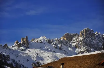a snow covered mountain with a house in front of it at Casa Tania in Pozza di Fassa