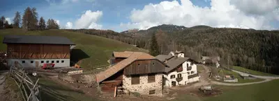 an aerial view of a house and a barn on a hill at THOMASERHOF in Redagno
