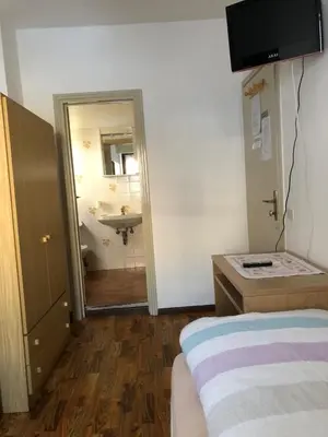 a room with a bed and a bathroom with a sink at B&B Astor in Alleghe