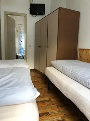 two beds in a room with a closet and a tv at B&B Astor in Alleghe