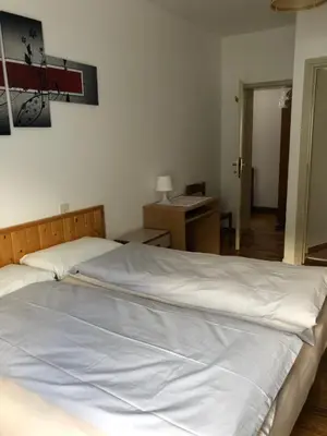 a large white bed in a bedroom with a desk at B&B Astor in Alleghe