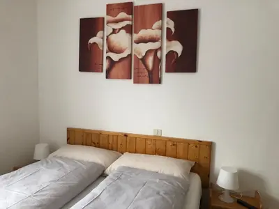 a bedroom with a bed with four paintings on the wall at B&B Astor in Alleghe