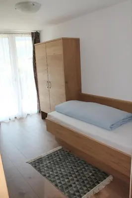 a bedroom with a bed and a cabinet and a rug at Garni Wiesenhof in Naturno
