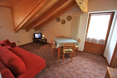 a living room with a red couch and a table at Cesa Roseda in Canazei