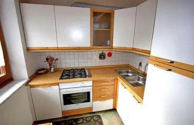a kitchen with white cabinets and a stove top oven at Cesa Roseda in Canazei