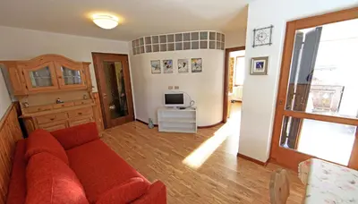 a living room with a red couch and a television at Cesa Roseda in Canazei