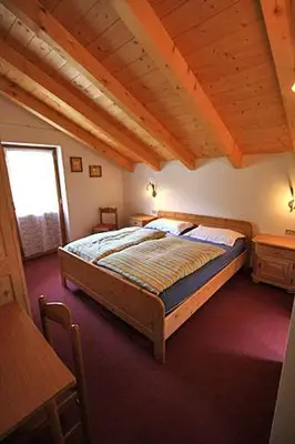 a bedroom with a bed and a wooden ceiling at Cesa Roseda in Canazei