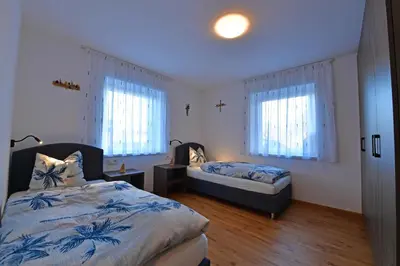 a bedroom with two beds and two windows at Lärchenheim Appartment in Castelrotto