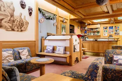a room with a bunk bed and two chairs at Hotel Coldai in Alleghe