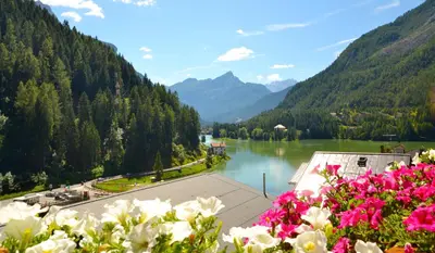 a view of a lake and mountains with flowers at Hotel Coldai in Alleghe