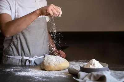 a person is sprinkling flour on a piece of bread at Ansitz Lidl in Tesimo