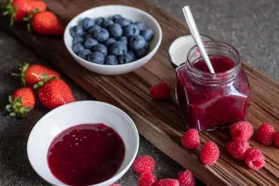 a wooden cutting board with berries and a jar of raspberry jam at Ansitz Lidl in Tesimo