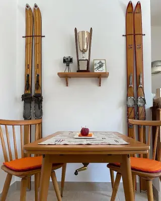 a table and two chairs with skis on a wall at Villa Maria Dolomites Vintage Home in Brunico