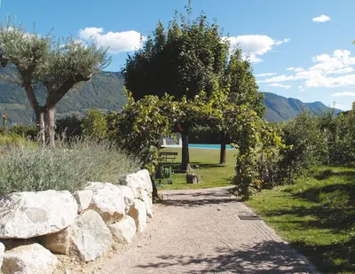 a stone path with trees and a stone wall at Ausserdorfer Apartments in Lana
