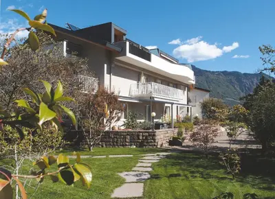 a large white house with a balcony and a yard at Ausserdorfer Apartments in Lana