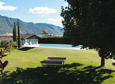 a park bench sitting in the grass next to a pool at Ausserdorfer Apartments in Lana