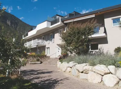 a large white building with a stone wall at Ausserdorfer Apartments in Lana