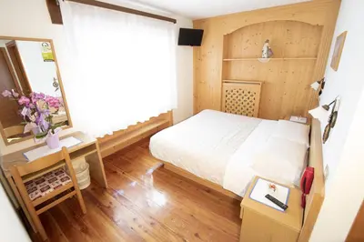 a small bedroom with a bed and a mirror at Hotel Edelweiss in Val di Zoldo