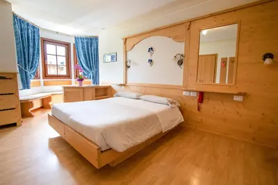 a bedroom with a large bed in a room with blue curtains at Hotel Edelweiss in Val di Zoldo