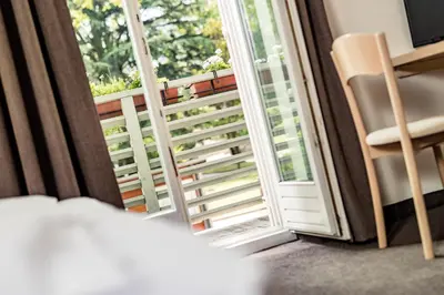 a bedroom with a door open to a balcony at Hotel Heide Park in Ora/Auer