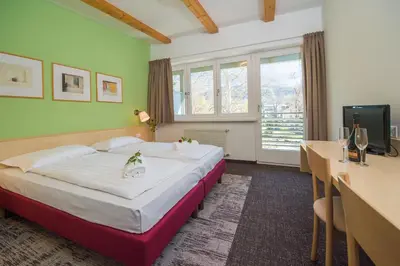 a hotel room with a large bed and a desk at Hotel Heide Park in Ora/Auer