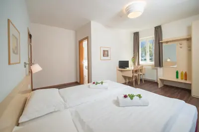 a bedroom with a large white bed with flowers on it at Hotel Heide Park in Ora/Auer