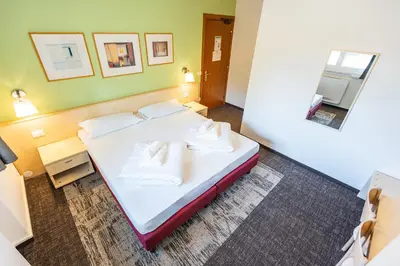 a room with a bed with white sheets and pillows at Hotel Heide Park in Ora/Auer