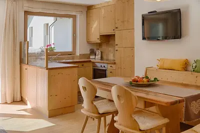 a kitchen with a wooden table with chairs and a television at Cademia in Ortisei