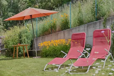 two red chairs and an umbrella in a yard at Cademia in Ortisei