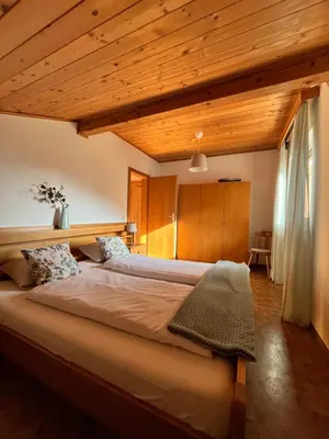 a large bed in a room with wooden ceilings at Voldersberghof in Cortaccia