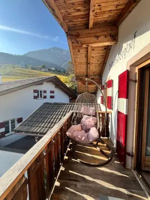 a rocking chair on the balcony of a house at Voldersberghof in Cortaccia