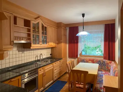 a kitchen with wooden cabinets and a table and a dining room at Pradat in La Valle