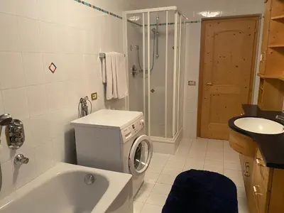 a bathroom with a tub and a washing machine at Pradat in La Valle