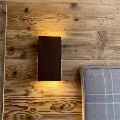 a light on a wooden wall with a sign on it at Piccolo gioiello di montagna in Villanova