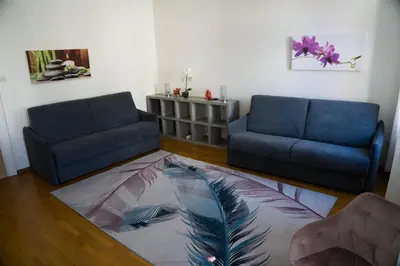 a living room with two blue couches and a rug at Casa Rudy in Bolzano