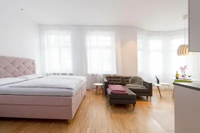 a white bedroom with a bed and a couch at Apartments Leonardo in Bolzano