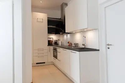a white kitchen with white cabinets and appliances at Apartments Leonardo in Bolzano