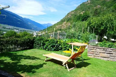 a chair sitting on the grass in a yard at Apartment Weitblick - Alpstay in Naturno
