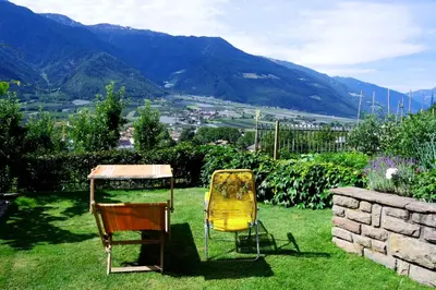 two chairs and a table in a yard with mountains at Apartment Weitblick - Alpstay in Naturno