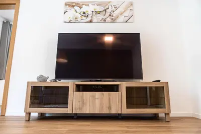 a flat screen tv sitting on top of a wooden entertainment center at Flow Apartments Margareta in Parcines