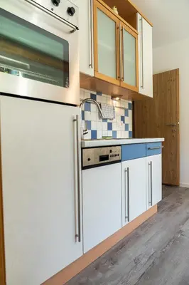 a kitchen with white cabinets and a sink at Flow Apartments Margareta in Parcines