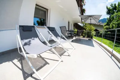 a pair of white chairs sitting on a patio at Flow Apartments Margareta in Parcines