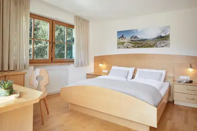 a bedroom with a bed and a desk and windows at daHoam Appartamenti in Rasùn di Sotto